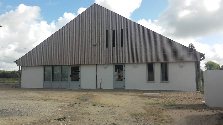 Bâtiment industriel avec toiture en tôle ondulée, fenêtres et portes en métal.