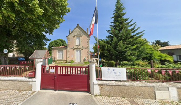Maison avec porte rouge, drapeau, arbre et panneau de signalisation.