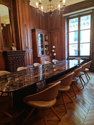 Salle à manger avec table en marbre, chaises, buffet et lustre.